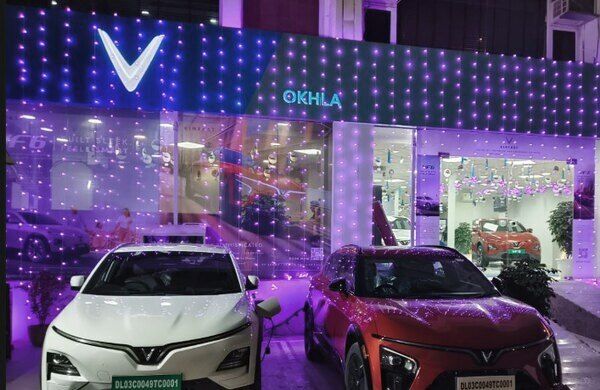 YouWe VinFast Okhla showroom lit up at night with a white and a red VinFast outside